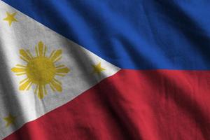 Philippines flag with big folds waving close up under the studio light indoors. The official symbols and colors in banner photo