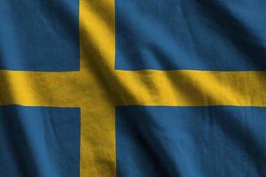 Sweden flag with big folds waving close up under the studio light indoors. The official symbols and colors in banner photo