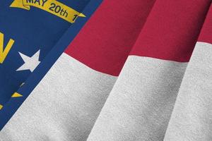North Carolina US state flag with big folds waving close up under the studio light indoors. The official symbols and colors in banner photo