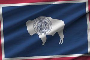 Wyoming US state flag with big folds waving close up under the studio light indoors. The official symbols and colors in banner photo