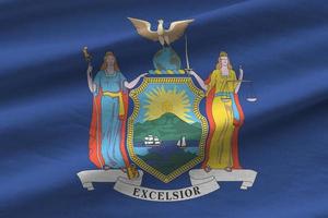 bandera del estado de nueva york con grandes pliegues ondeando de cerca bajo la luz del estudio en el interior. los símbolos y colores oficiales en banner foto