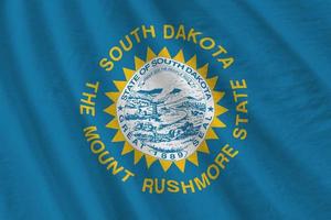 South Dakota US state flag with big folds waving close up under the studio light indoors. The official symbols and colors in banner photo