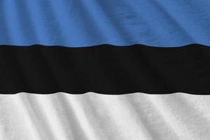 Estonia flag with big folds waving close up under the studio light indoors. The official symbols and colors in banner photo