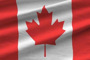 Canada flag with big folds waving close up under the studio light indoors. The official symbols and colors in banner photo