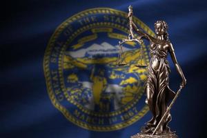 Nebraska US state flag with statue of lady justice and judicial scales in dark room. Concept of judgement and punishment photo