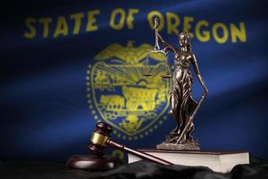 Oregon US state flag with statue of lady justice, constitution and judge hammer on black drapery. Concept of judgement and guilt photo