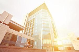 Young girl uses a smartphone on the office building background photo