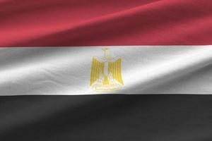 Egypt flag with big folds waving close up under the studio light indoors. The official symbols and colors in banner photo