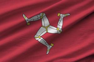 Isle of Man flag with big folds waving close up under the studio light indoors. The official symbols and colors in banner photo