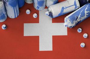 Switzerland flag and few used aerosol spray cans for graffiti painting. Street art culture concept photo