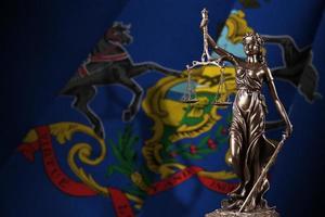Pensilvania, bandera del estado de EE. UU. Con estatua de la dama de la justicia y escalas judiciales en una habitación oscura. concepto de juicio y castigo foto
