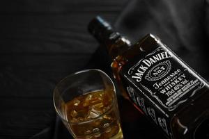 KYIV, UKRAINE - MAY 4, 2022 Jack Daniels original alcohol bottle on wooden table with black fabric photo