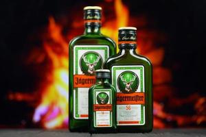 KYIV, UKRAINE - MAY 4, 2022 Jagermeister original alcohol bottle on wooden table with red fireplace