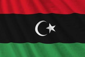 Libya flag with big folds waving close up under the studio light indoors. The official symbols and colors in banner photo