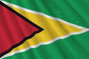 Guyana flag with big folds waving close up under the studio light indoors. The official symbols and colors in banner photo