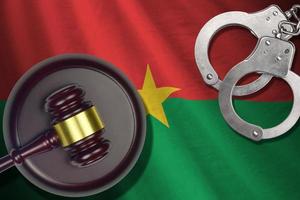 Burkina Faso flag with judge mallet and handcuffs in dark room. Concept of criminal and punishment, background for judgement topics photo