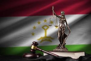 Tajikistan flag with statue of lady justice, constitution and judge hammer on black drapery. Concept of judgement and guilt photo