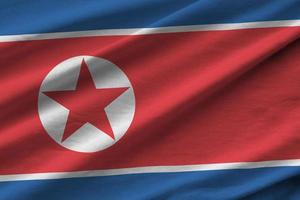 North Korea flag with big folds waving close up under the studio light indoors. The official symbols and colors in banner photo