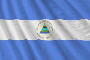 Nicaragua flag with big folds waving close up under the studio light indoors. The official symbols and colors in banner photo