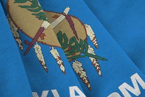 Oklahoma US state flag with big folds waving close up under the studio light indoors. The official symbols and colors in banner photo