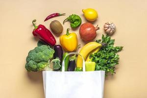 bolsa de papel ecológica con vegetales verdes orgánicos crudos aislados en fondo beige plano, vista superior cero desperdicio, concepto libre de plástico dieta saludable y desintoxicación, concepto de agricultura foto