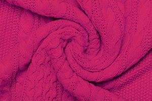 The texture of warm knitted sweater. Beautiful handmade knitted repeating pattern. Demonstrating Pantone color of the year 2023 viva magenta photo