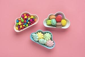 colorful candies - lollipops, meringues, macaroon in bowl in shape of cloud isolated on pink background Flat lay Top View Knolling Unhealthy and tasty food creative concept Holiday card photo