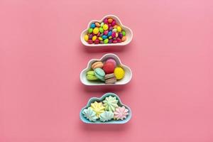 colorful candies - lollipops, meringues, macaroon in bowl in shape of cloud isolated on pink background Flat lay Top View Knolling Unhealthy and tasty food creative concept Holiday card photo