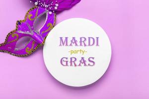 Mardi gras lettering. Congratulation card with mask on white podium on violet background Top view 2022 Mardi Gras Parade Schedule photo