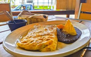 Mexican omelet eggs black beans potatoes nachos on white plate. photo