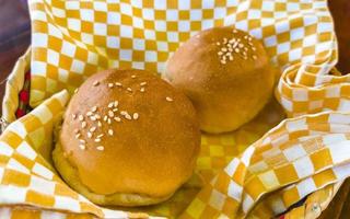 Delicious round buns with sesame seeds on wooden table Mexico. photo