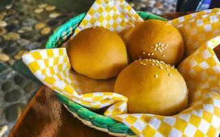 Delicious round buns with sesame seeds on wooden table Mexico. photo