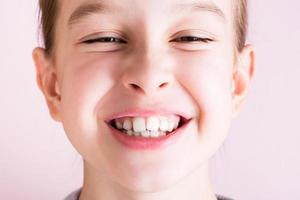 Portrait of a girl with crooked teeth on a pink background. Dentistry and orthodontics photo