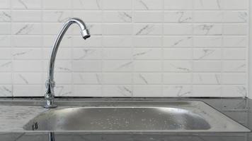 Stainless steel faucet mounted on the sink. Decorated with black tone tiles and white floors photo