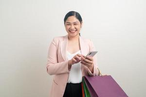 mujer asiática que usa un teléfono inteligente con una bolsa de compras a mano foto