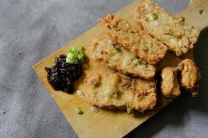 fried tempeh on a cutting board with soy sauce on the concrete floor photo