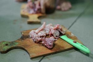 Fresh chicken meat is cut on a cutting board in a traditional market photo