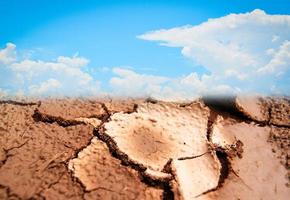 Ground broken drought land cracked soil and blue sky clouds photo