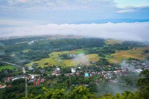 Top view landscape with fog misty cover village in the morning and mountain background photo