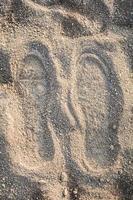 Shoe track on sand Imprint footprint on ground traces of feet texture background photo