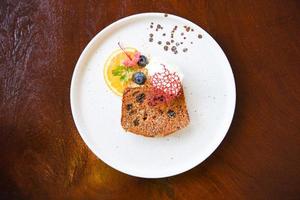 pastel de zanahoria en plato blanco - postre casero delicioso pastel con arándano naranja y azúcar glaseado sobre fondo de madera foto