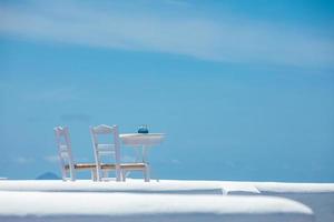Romantic table set-up in Santorini Greece. White architecture and table for two. Love concept in romantic travel destination, summer holiday or vacation concept. photo