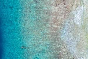 Aerial sea view, top view of amazing nature ocean background. Bright blue water colors, lagoon beach with waves splashing at sunny day. Flying drone photo, amazing nature landscape with coral reef photo