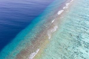 Aerial sea view, top view of amazing nature ocean background. Bright blue water colors, lagoon beach with waves splashing at sunny day. Flying drone photo, amazing nature landscape with coral reef photo