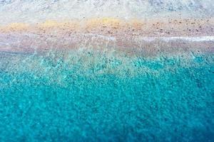 vista aérea al mar, vista superior del increíble fondo del océano natural. colores de agua azul brillante, playa de la laguna con olas salpicando en el día soleado. foto de drones voladores, asombroso paisaje natural con arrecife de coral