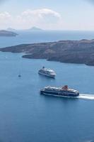 Greece, Santorini 05.08.19 - Santorini Greece, aerial caldera view ocean of ferry and passenger cruise ship boats passing true. Sea transportation in famous european travel destination photo