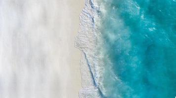 Summer seascape beautiful waves, blue sea water in sunny day. Top view from drone. Sea aerial view, amazing tropical nature background. Beautiful bright sea with waves splashing and beach sand concept photo