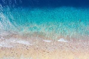 vista aérea al mar, vista superior del increíble fondo del océano natural. colores de agua azul brillante, playa de la laguna con olas salpicando en el día soleado. foto de drones voladores, asombroso paisaje natural con arrecife de coral