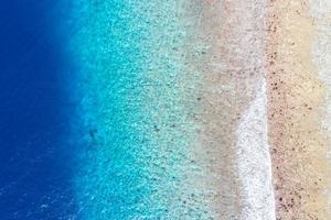 Aerial sea view, top view of amazing nature ocean background. Bright blue water colors, lagoon beach with waves splashing at sunny day. Flying drone photo, amazing nature landscape with coral reef photo