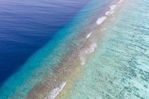 Aerial sea view, top view of amazing nature ocean background. Bright blue water colors, lagoon beach with waves splashing at sunny day. Flying drone photo, amazing nature landscape with coral reef photo